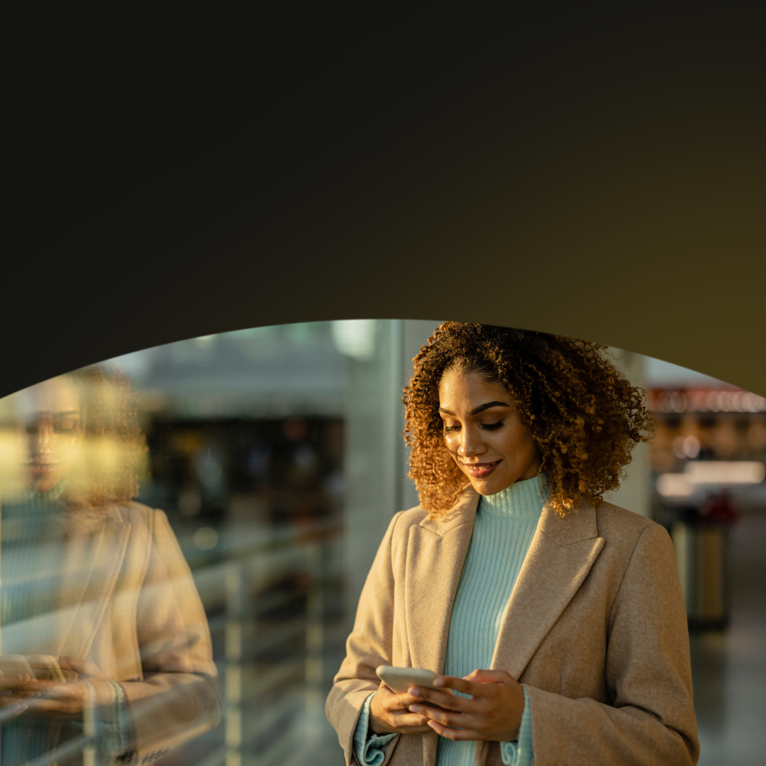 Woman using her phone looking out the window of an office building