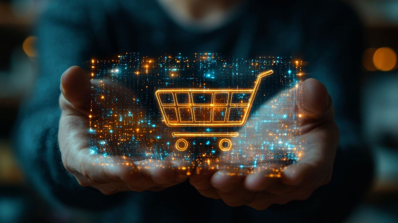 A shopping cart superimposed on top of a mobile phone screen with blue and orange  dots being held by a person's hands . 