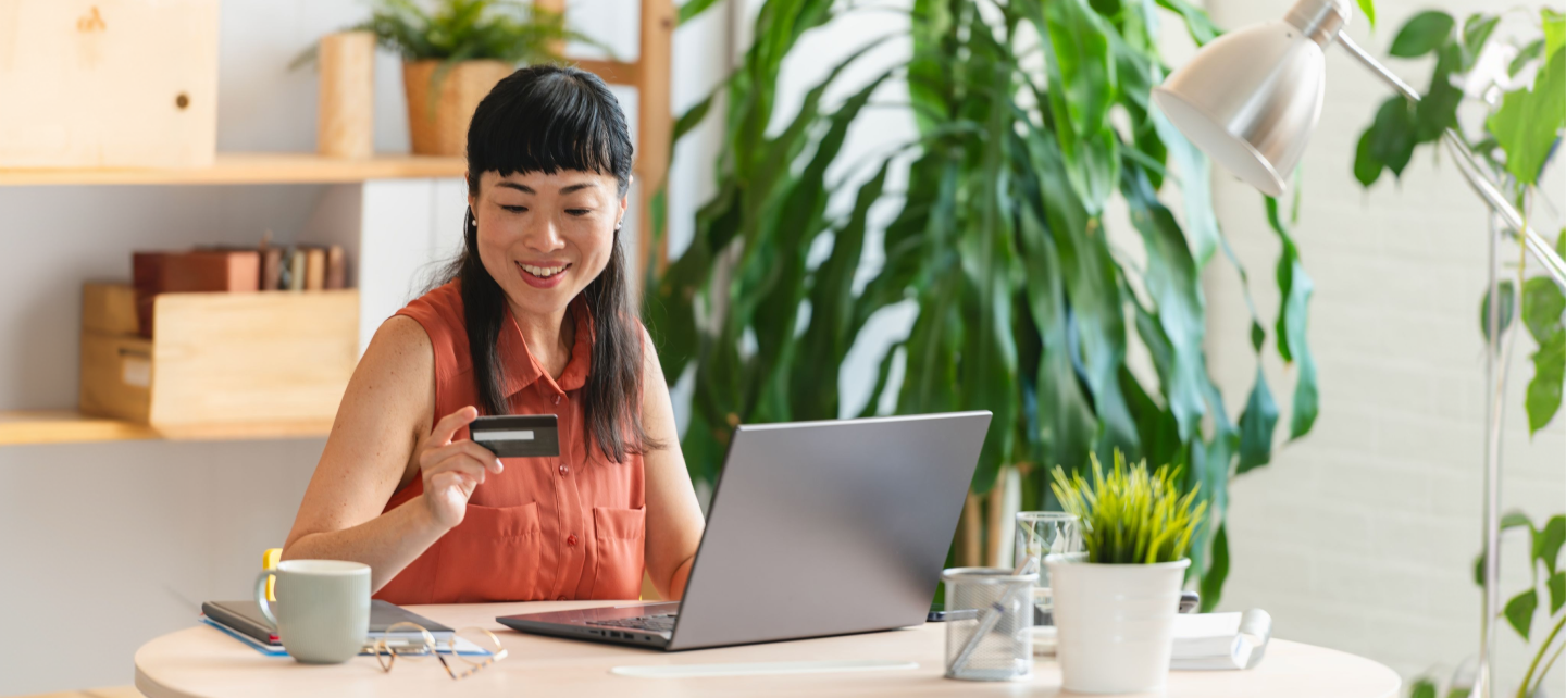 Mujer haciendo una compra usando su tarjeta en su computadora portátil