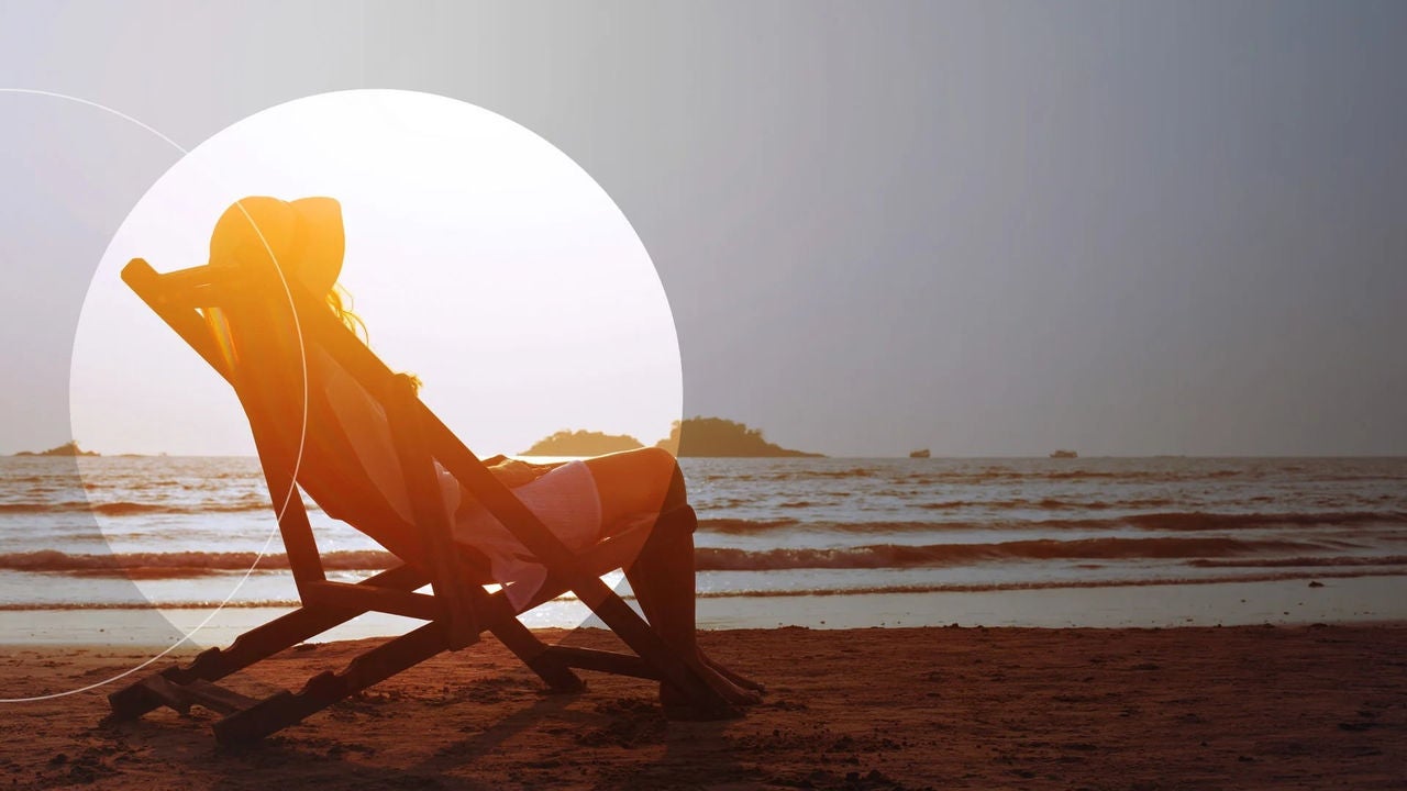 סצנת חוף ובה אישה יושבת על כיסא, נהנית מהשמש ומנוף האוקיינוס.