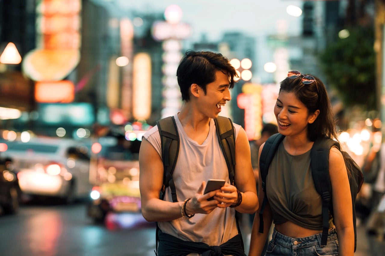 couple using smart phone while walking in city center