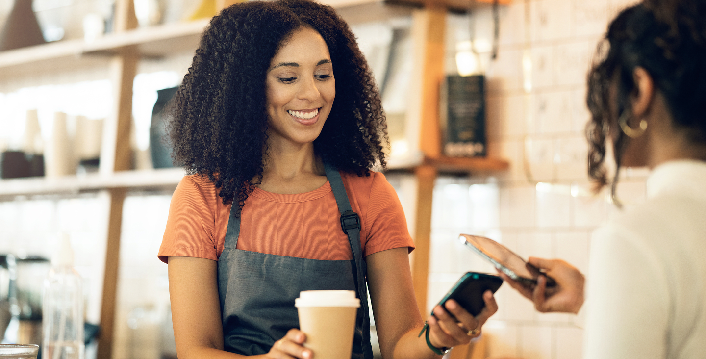 Two women paying by tap on phone payment for coffee