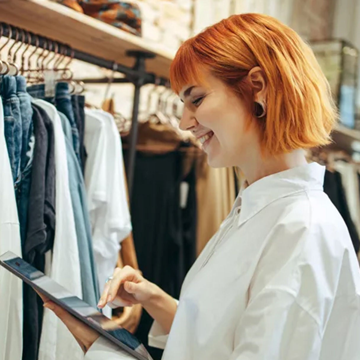 Smiling woman browsing clothes on a tablet.