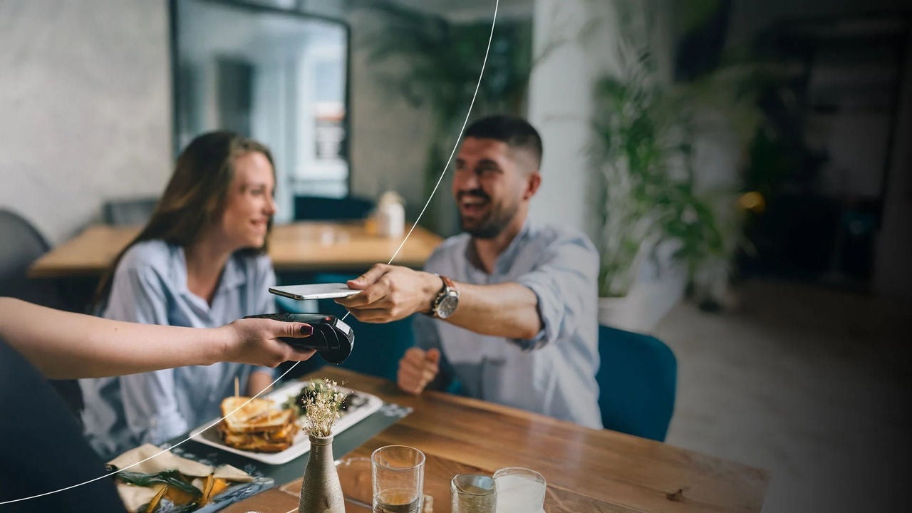 גבר משלם ללא מגע בטלפון נייד במסעדה.