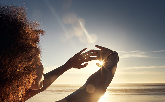 woman holding hands in front of sunset