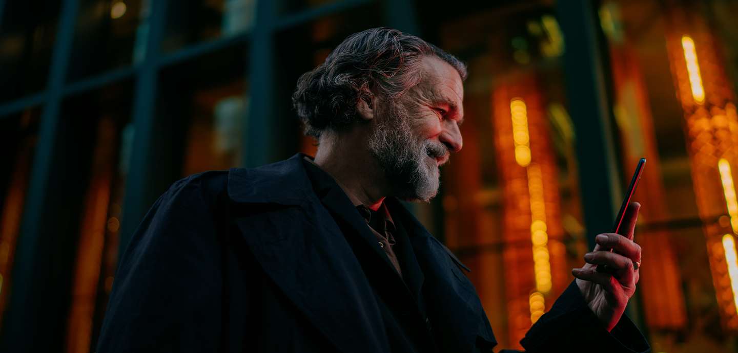 Man with a beard on his phone at night