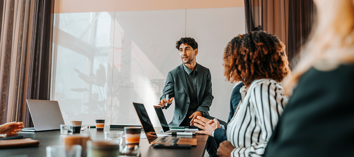 Young male entrepreneur brainstorming colleagues sitting in board room at office