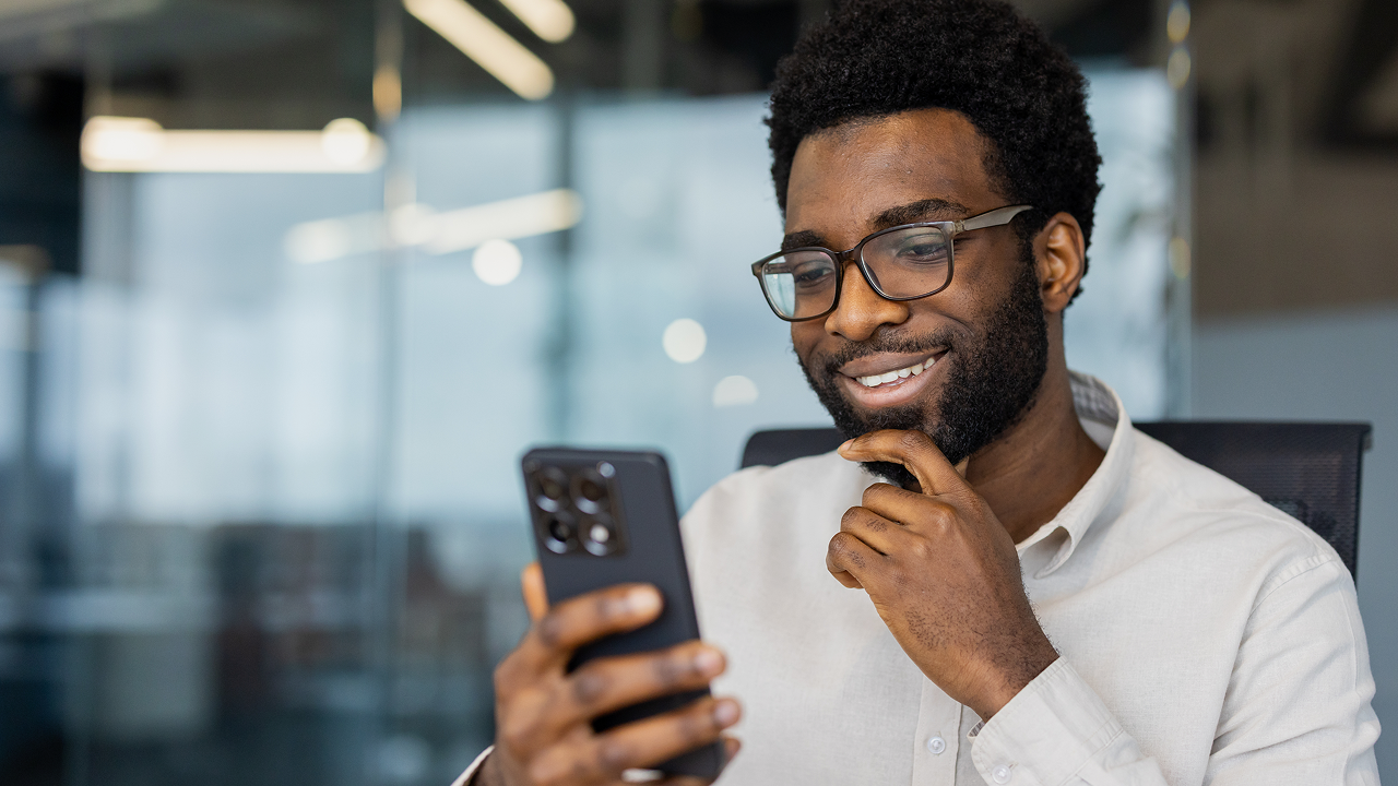 A man with a beard and glasses is looking at his phone