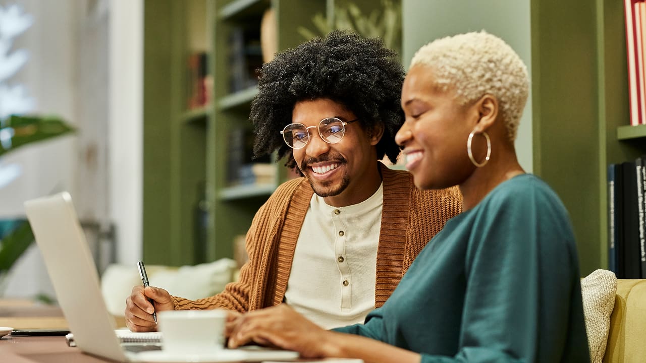 smiling couple working together on a laptop computer