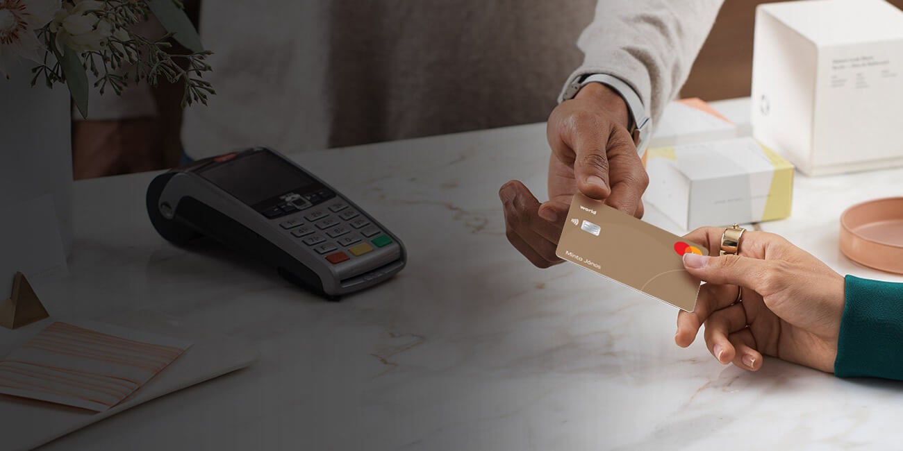 Vásárló Mastercard bankkártyával fizet egy üzletben a pénztárnál, háttérben bankkártya-elfogadó terminállal