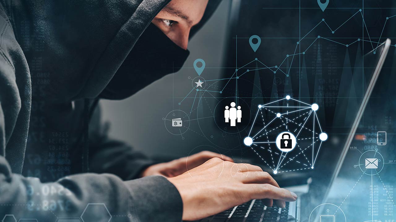 Man wearing hoodie, working on a laptop.