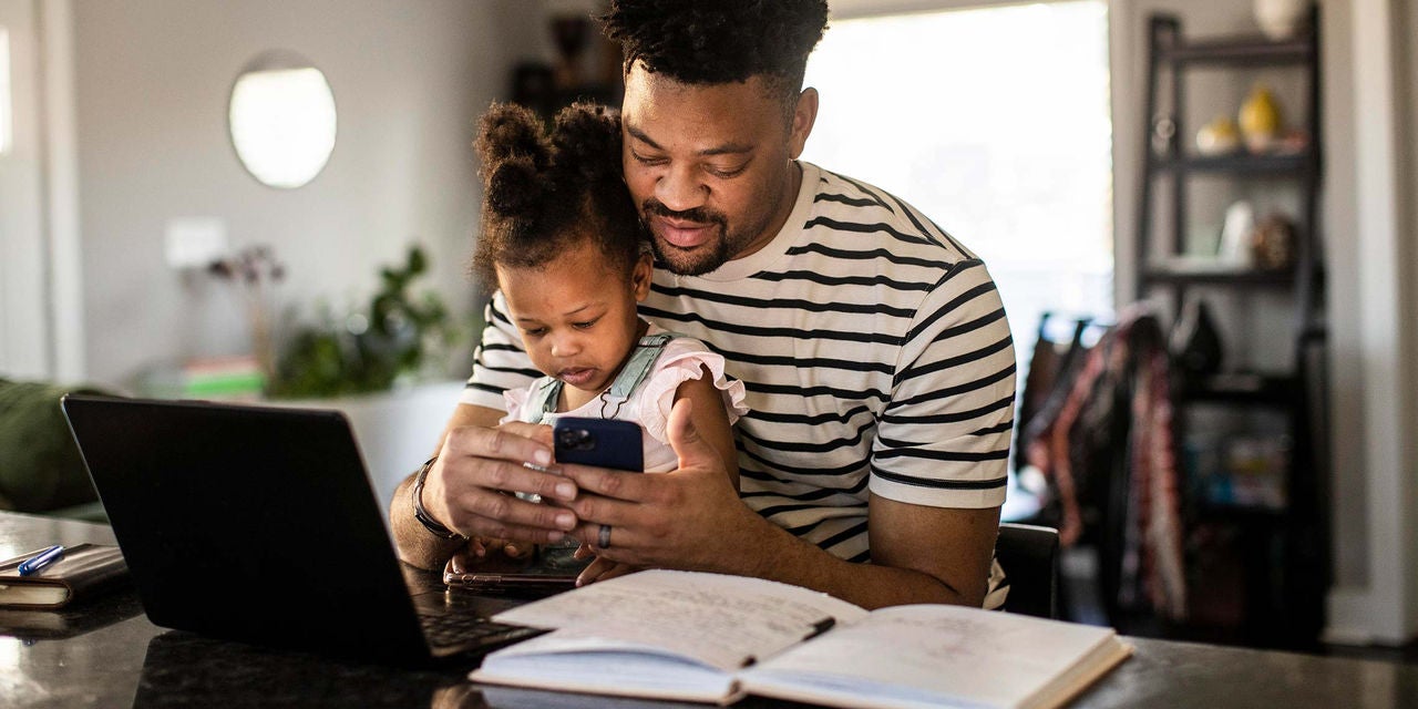 Father and daughter sitting together looking at mobile phone.