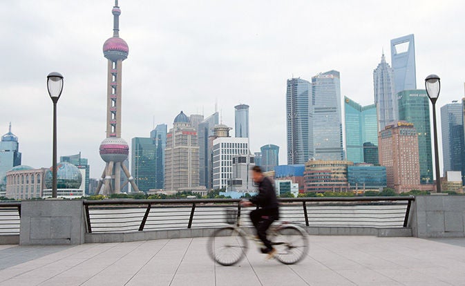 Man riding bicycle with city skyline in the background.