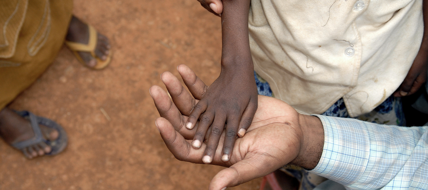 Young boy's hand above elder man's hand