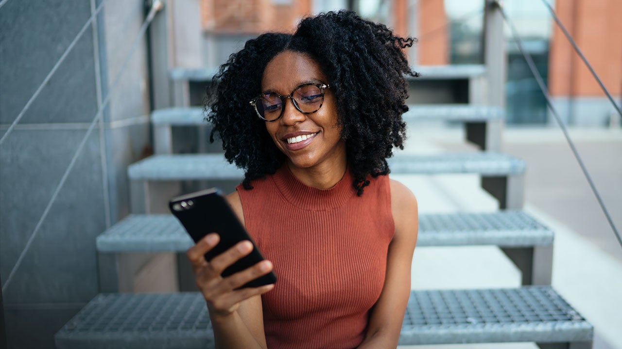 Woman checking her phone, sitting on stairs.