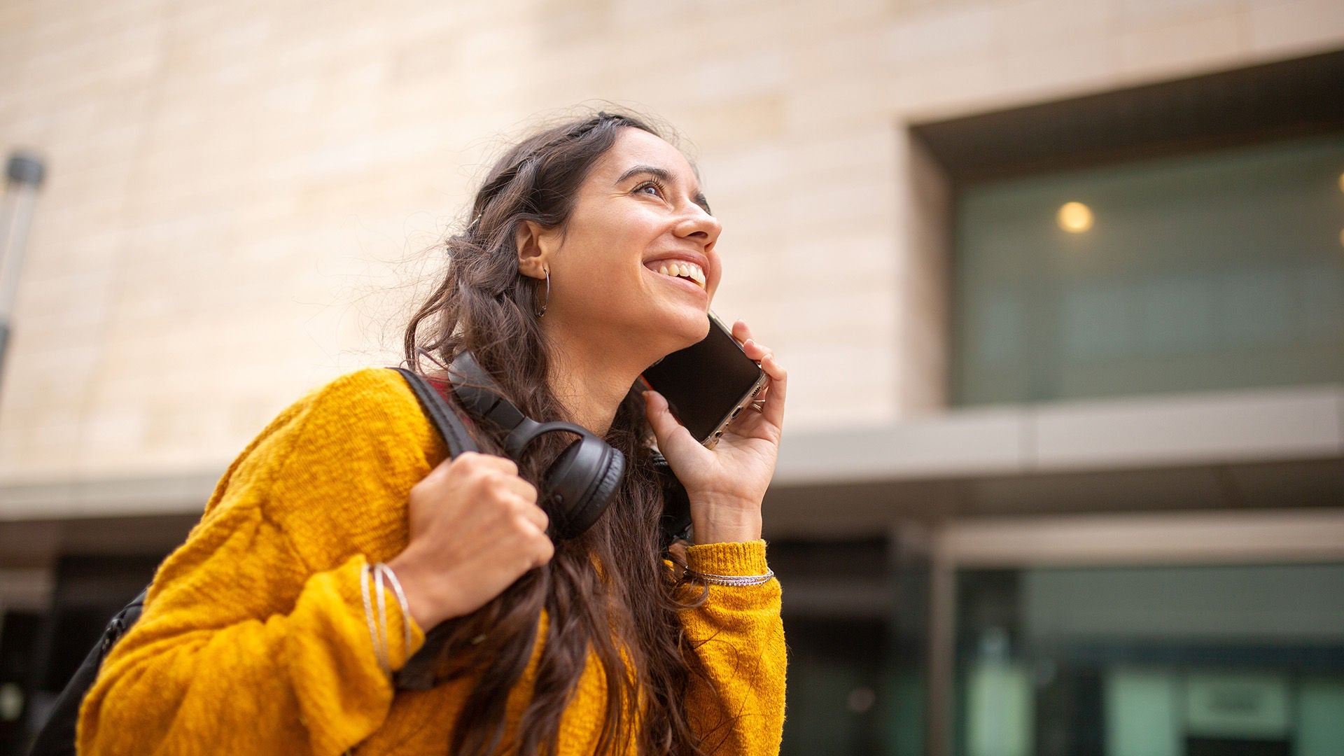 Woman on phone walking outside with backpack on