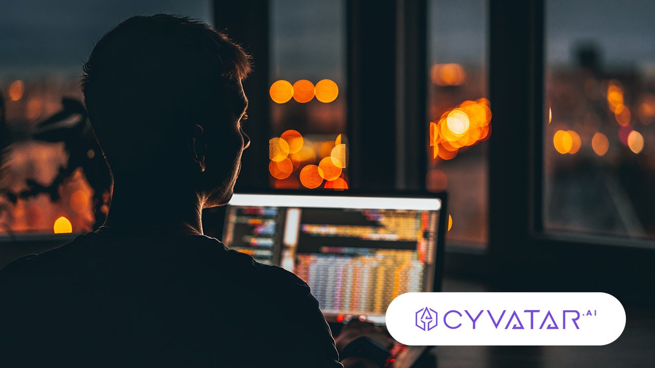 Man in a dark room, working on a laptop. Cyvatar logo.