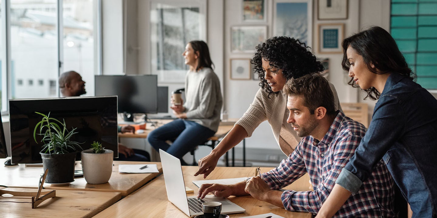 Three coworkers collaborating at a desk