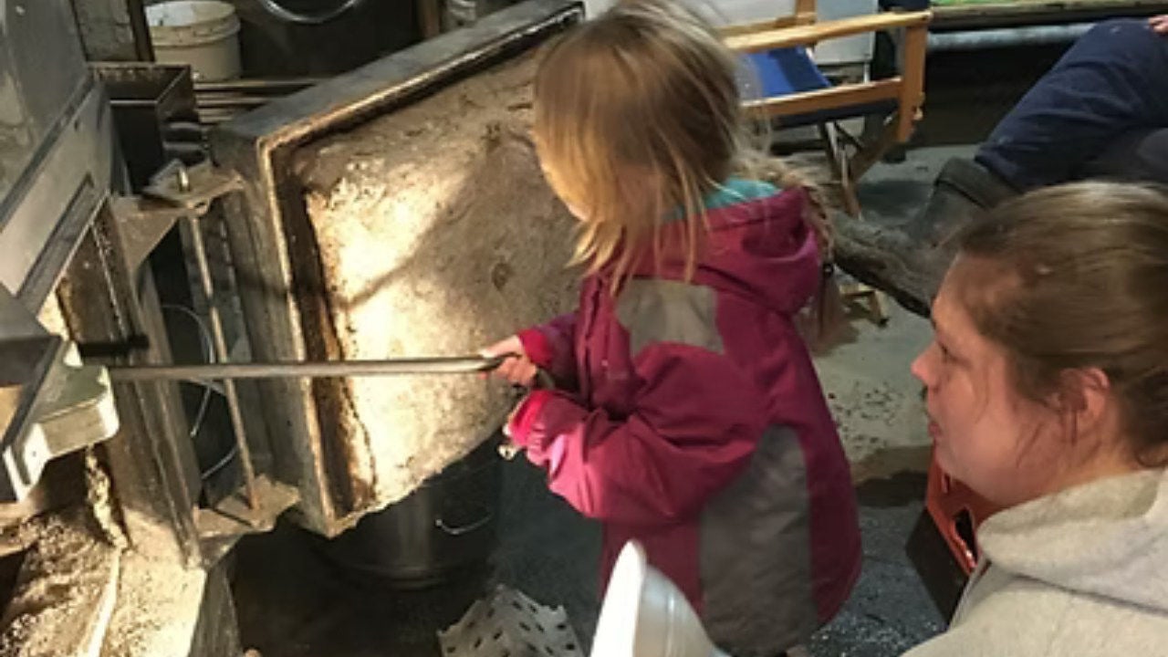 Ashley-Morgan stokes a fire in the Ballard sugarhouse as Kimberly Ballard watches. 
