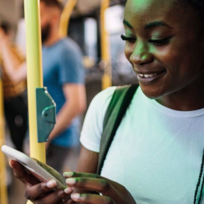A person smiling at a smartphone inside a bus