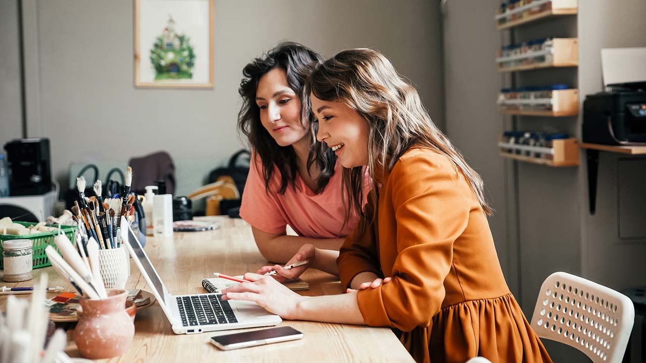 Two colleagues in creative workshop lookin at laptop.