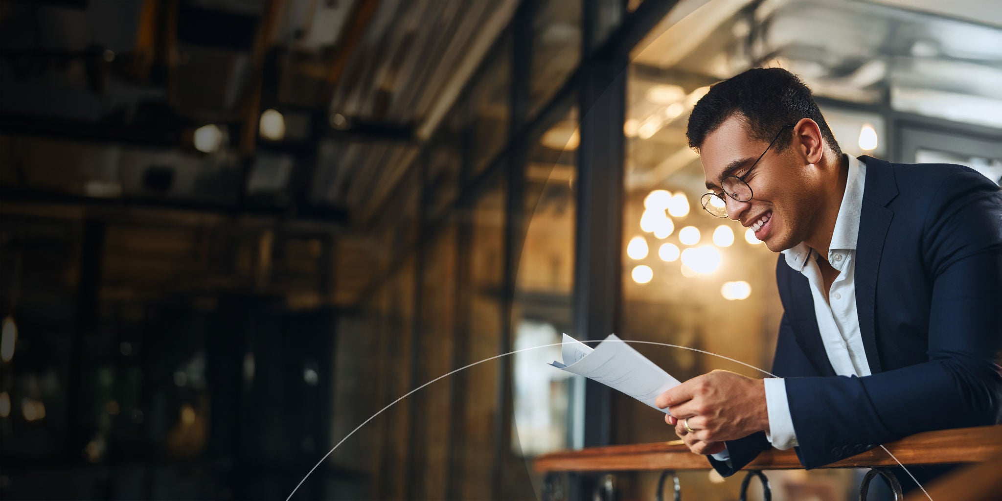 A man dressed in a suit is focused on reading a document in a professional setting.