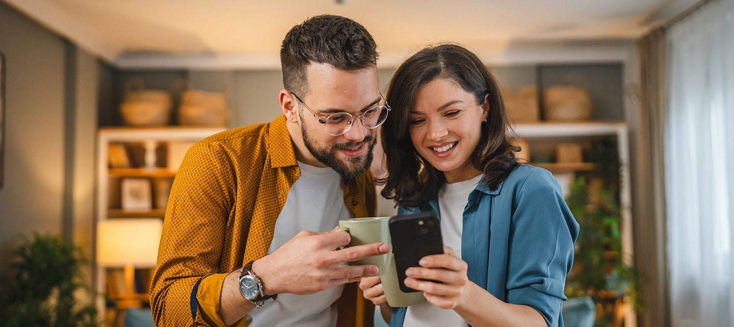 A man and a woman smiling while looking at a phone