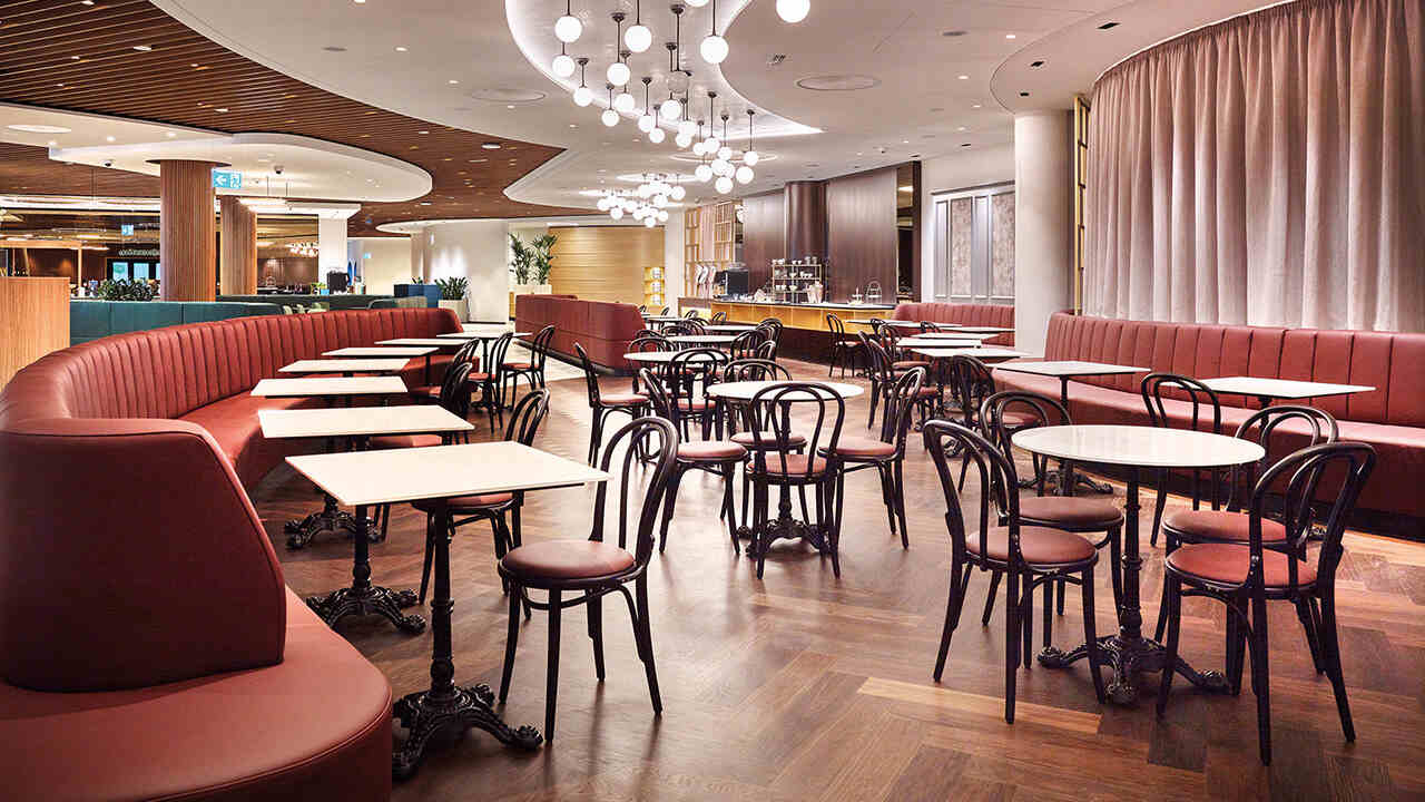 Beltéri éttermi tér asztalokkal és székekkel, íves padülésekkel, csillárvilágítással és parkettázott padlóval