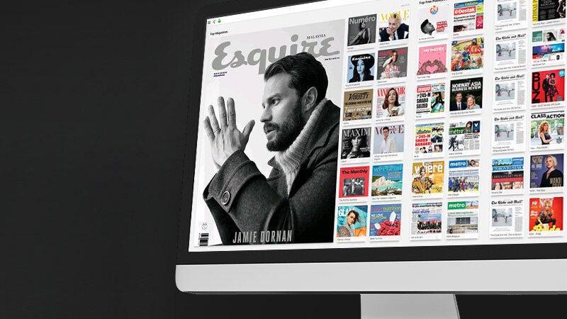 Asztali monitor kijelzőjén digitális magazin címlap és több újságborító rácsos elrendezésben, sötét háttér előtt