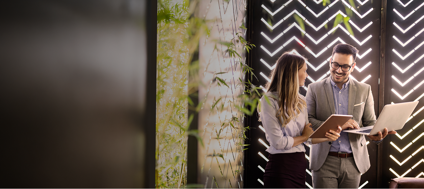 A man and woman standing in front of a laptop