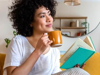 Woman drinking coffee reading a book
