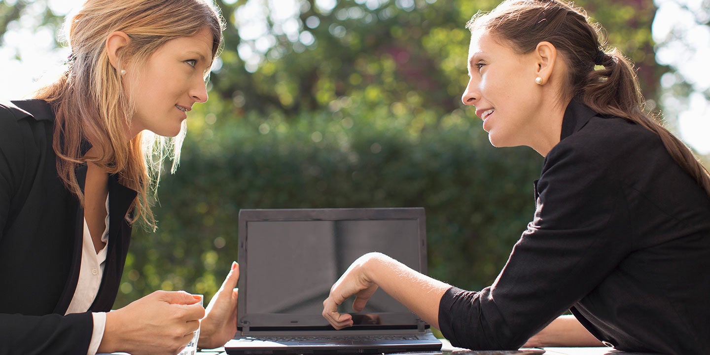 Businesswomen having a discussion on laptop at outdoor cafe