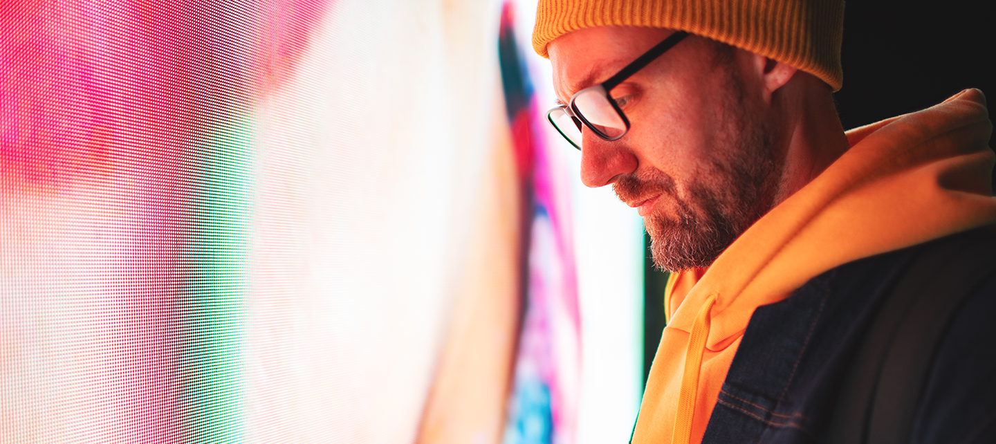 Mna looking at phone in front of a screen