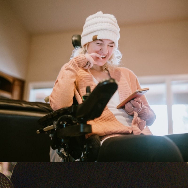 A woman in a wheelchair looks at a smartphone screen. 