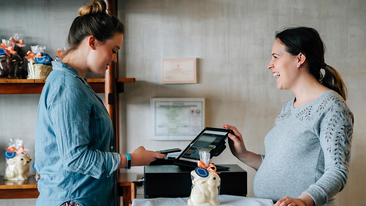 Joyful owner and female customer making mobile payment at a store.