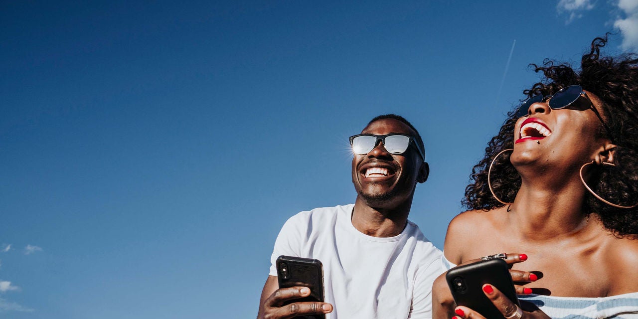Happy man and woman laughing while looking at a phone