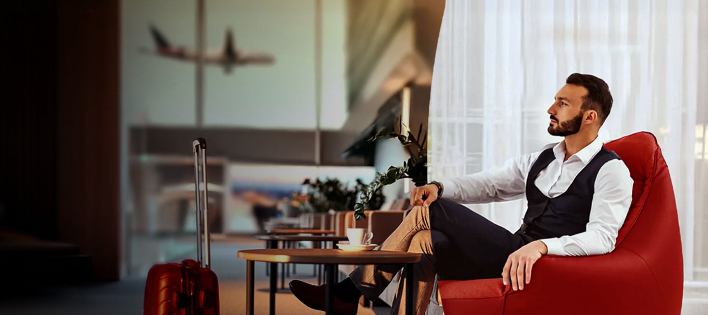 man sitting in red chair at the airport