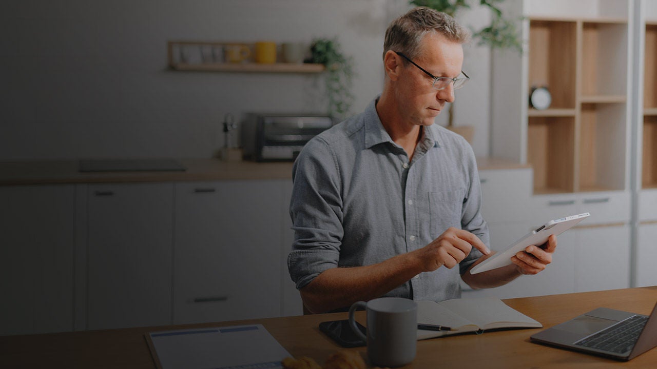 Man sitting at a table in the kitchen working on his laptop