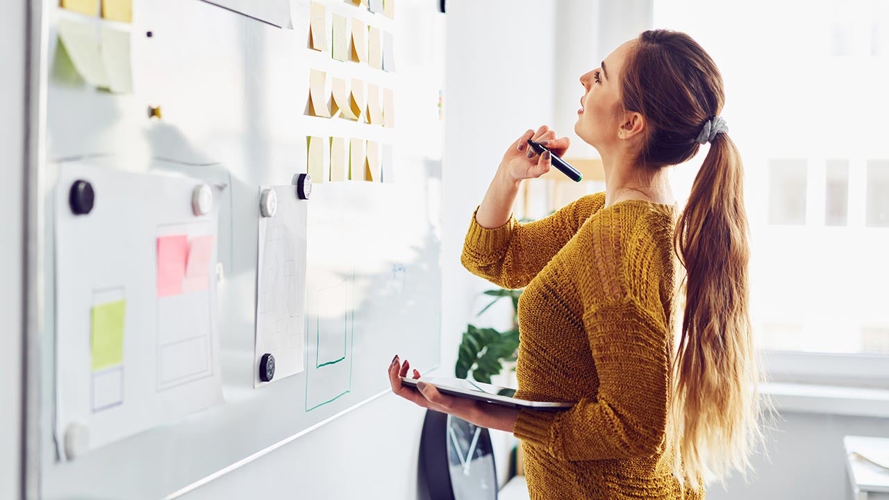 Woman pondering at white board.
