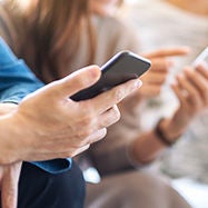 Dos personas sosteniendo teléfonos celulares.