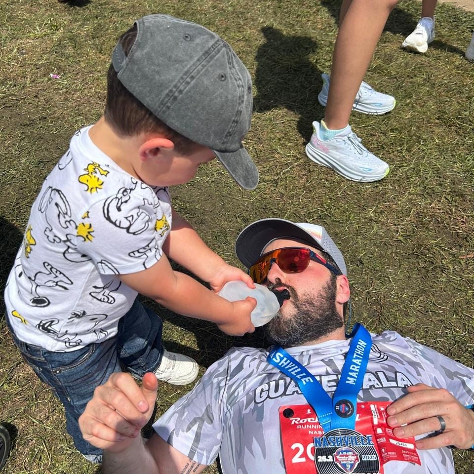 Sebastian del Buey's son helps him drink from a bottle after running a marathon. 