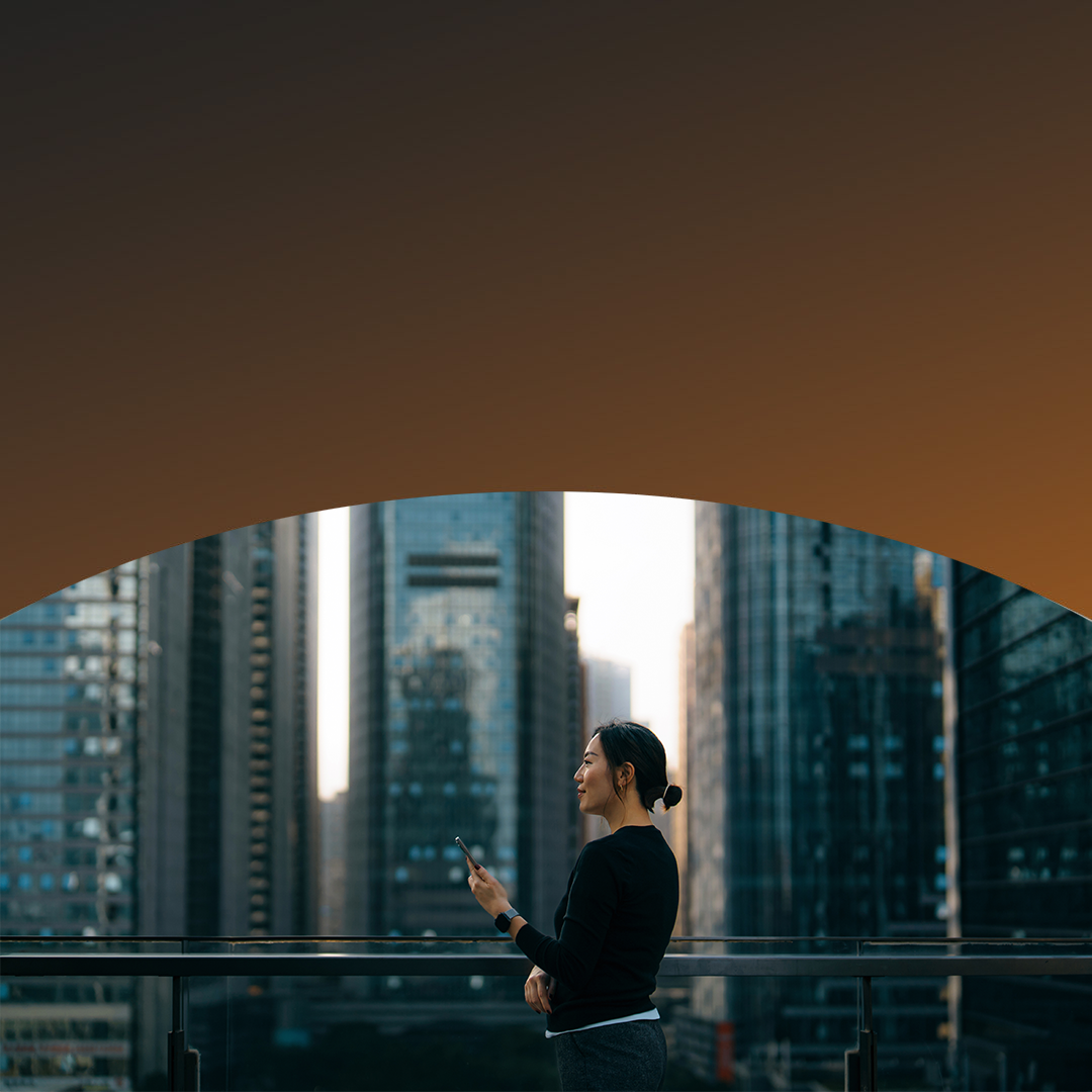 Smiling woman holding her phone standing on a roof