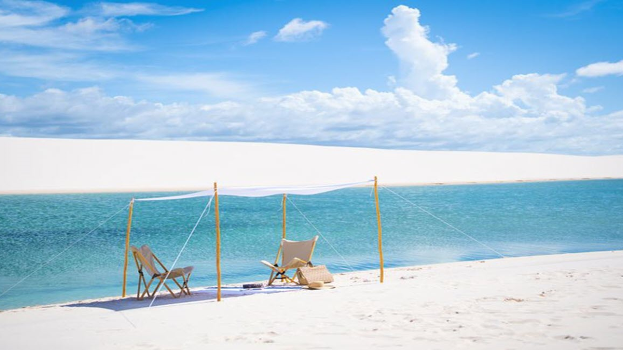 Man on a laptop with suitcases in a hotel room.