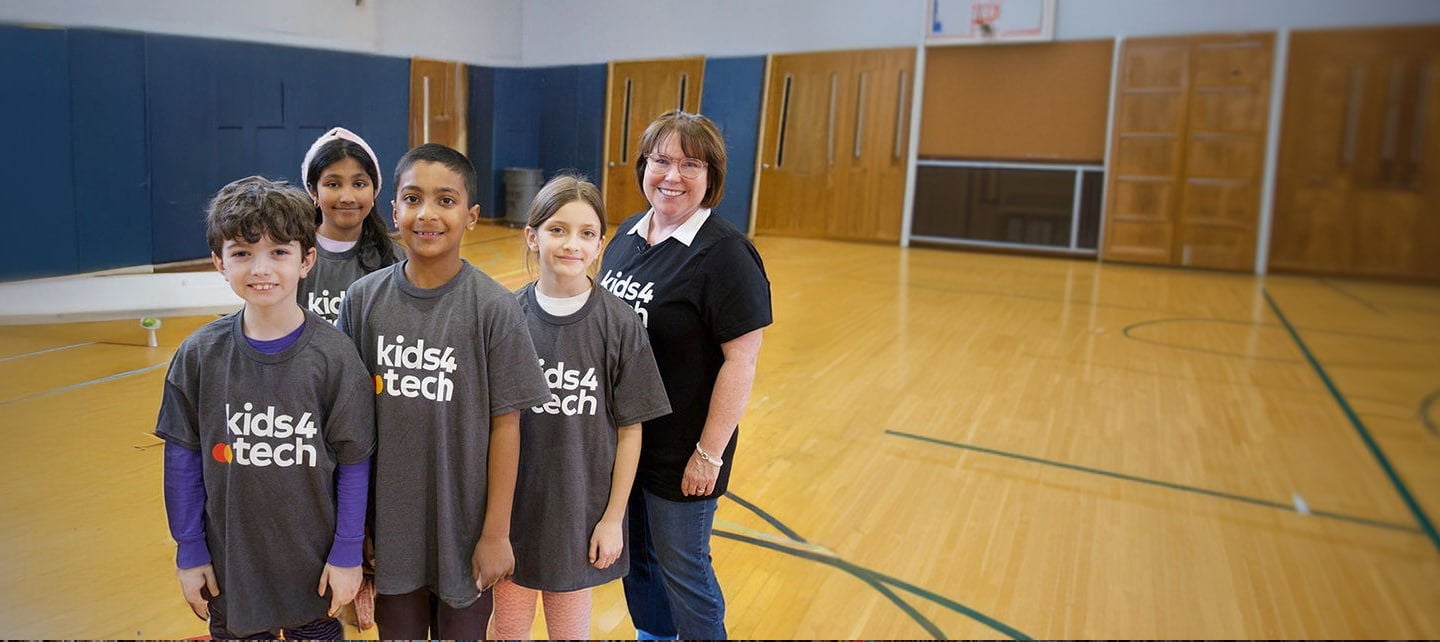 أربعة أطفال ومعلمهم يرتدون قمصان 'كيدز 4 تك'