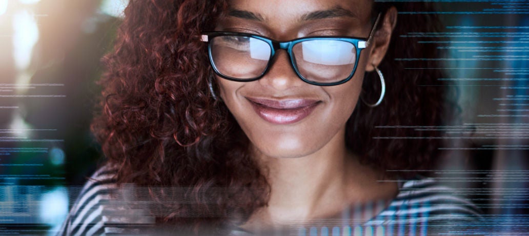 Mulher olhando para o sistema bancário aberto na tela do computador, sorrindo.