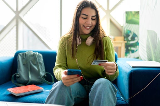 Young smiling brunette using her credit card to pay the bills