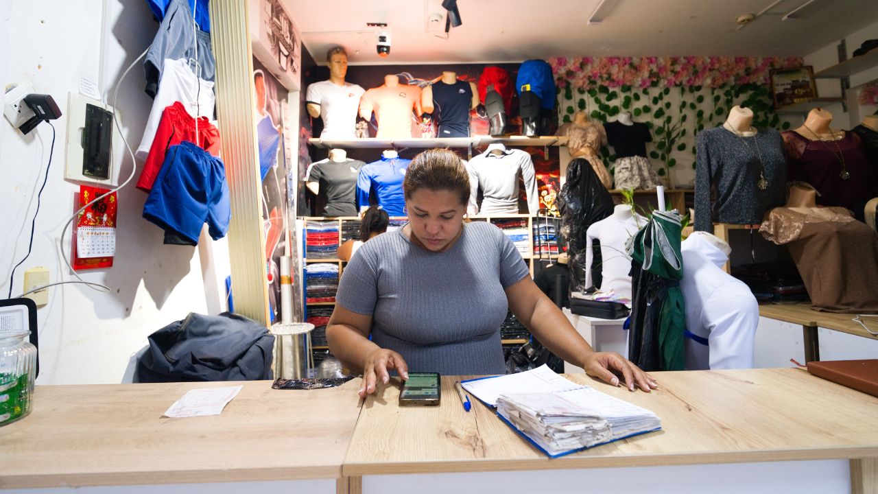Fabiola looks at a digital app at the counter in her sportwear store. 