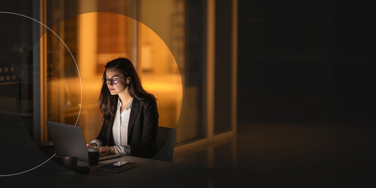 אישה עובדת ליד שולחנה מאוחר בלילה במשרד.