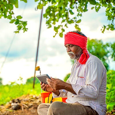 Man looking at tablet while sitting at a farm.
