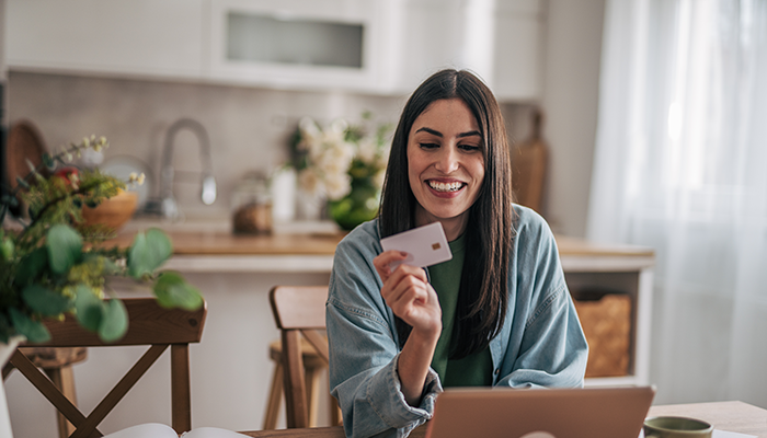 Woman shopping on her computer with her card in hand